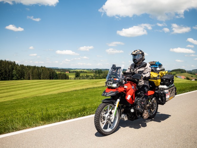 A motorcycle with dguard rides fully loaded on a road