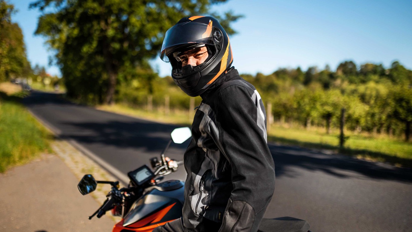 the motorcyclist smiles into the camera, a dguard is built into his motorcycle.